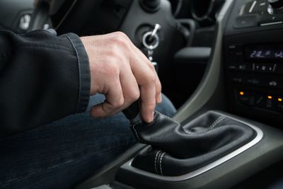 Midsection of man holding gearshift while driving car