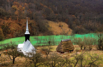High angle view of church on field by polluted lake against forest