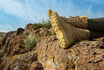 Low section of man standing on rock against sky