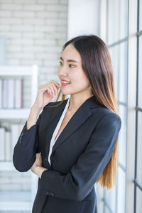 Portrait of a beautiful young woman standing against wall