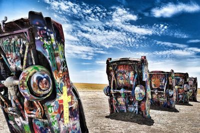 Graffiti on old rusty metallic structure at beach against sky