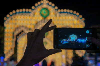 Hand photographing illuminated smart phone at night