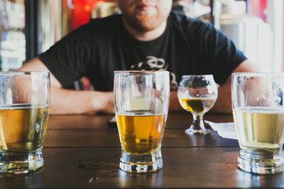 Midsection of man sitting by table with beer