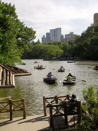 Boats sailing in river by city against sky