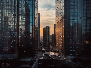 Modern buildings in city against sky during sunset