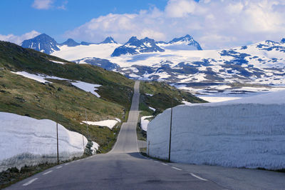 Road amidst snowcapped mountains against sky