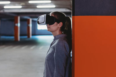 Woman with vr goggles in empty garage with led lights