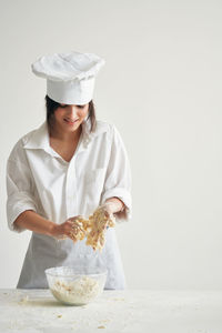 Smiling chef preparing food against white background