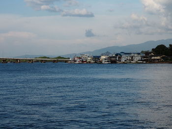 Scenic view of sea by townscape against sky