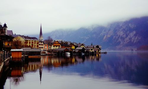 Buildings by lake against sky