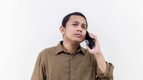 Portrait of young man looking away against white background