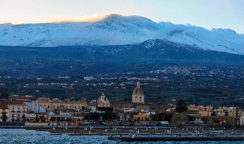 Aerial view of the cityscape and etna volcano against the sky