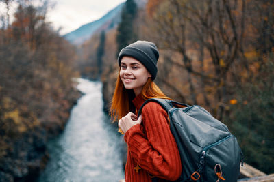 Young woman looking away while standing on tree during winter