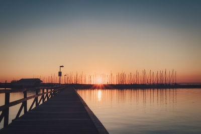 Pier over lake against sky during sunset