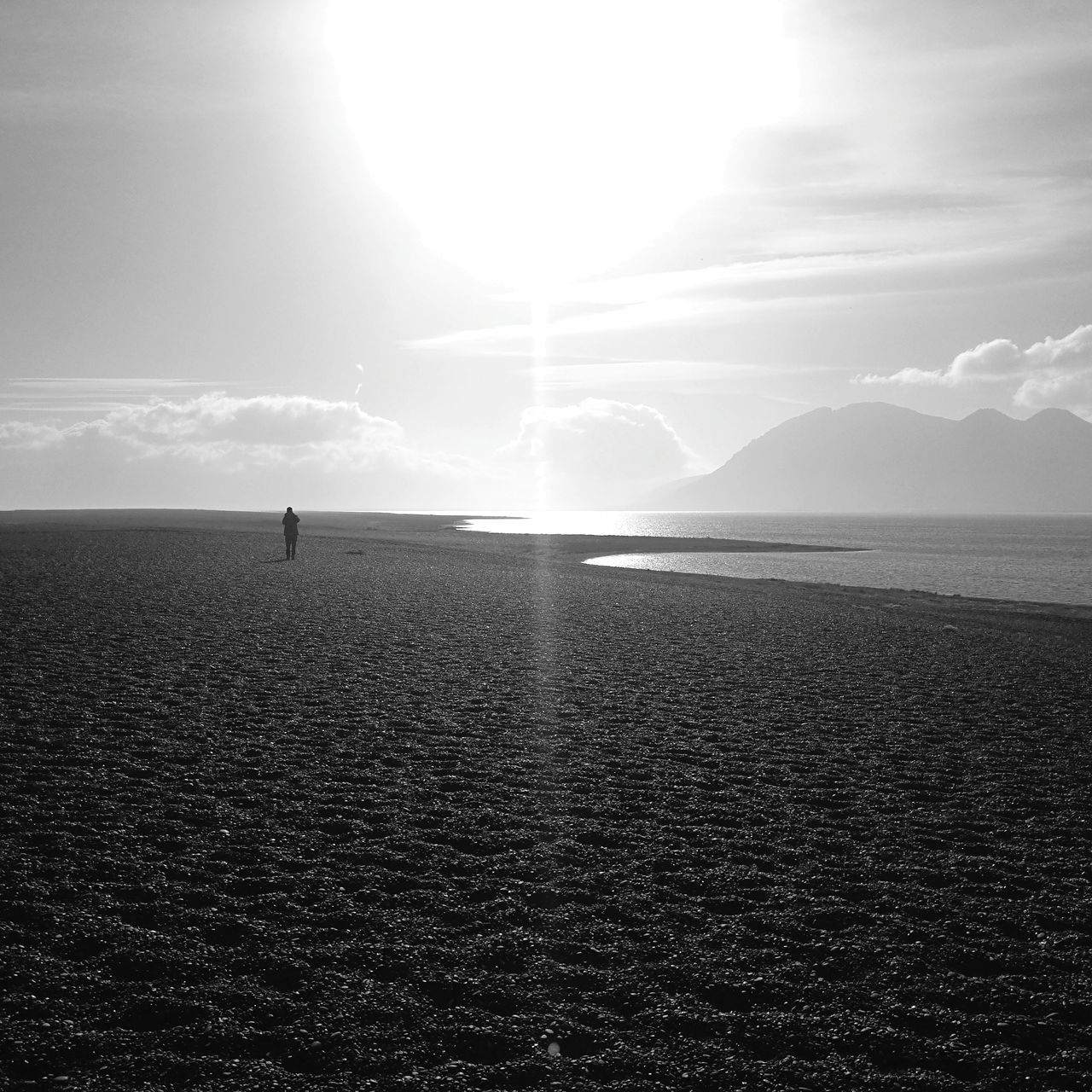 sky, scenics - nature, beauty in nature, sea, water, tranquil scene, tranquility, sunlight, land, cloud - sky, nature, one person, silhouette, horizon, non-urban scene, real people, sun, sunbeam, unrecognizable person, horizon over water, outdoors, bright, lens flare