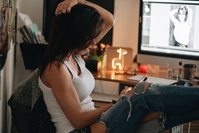 Side view of woman sitting at home