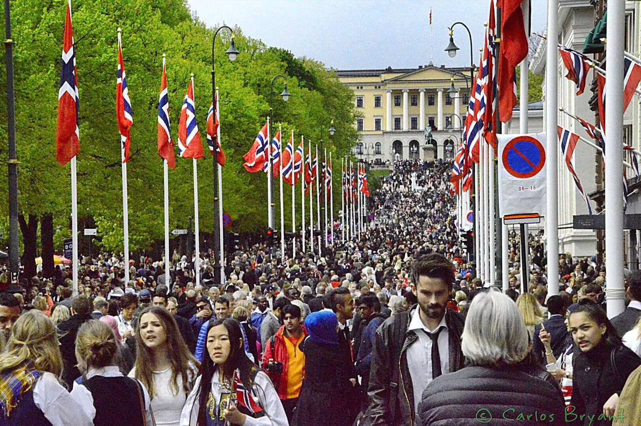 large group of people, men, person, lifestyles, leisure activity, crowd, building exterior, flag, built structure, tree, architecture, street, sky, city, celebration, day, mixed age range, outdoors, walking