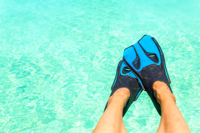 Low section of person wearing diving flippers over swimming pool