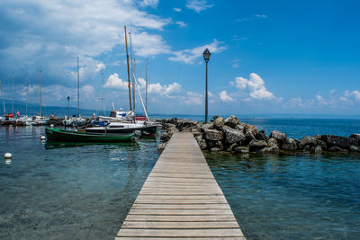 Boats moored at harbor against sky