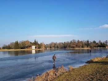 Man standing by lake against sky