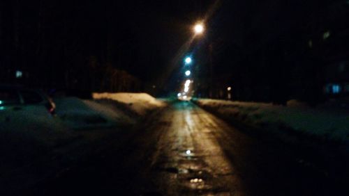 Road passing through illuminated street at night