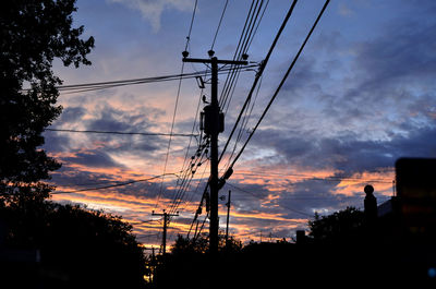 Low angle view of silhouette electricity pylon against sky during sunset