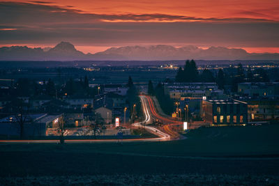 Illuminated cityscape against sky at sunset