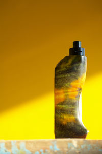 Close-up of yellow bottle against wall