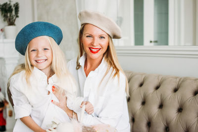 Young funny happy fair long hair mom and cute girl having fun together at living room, happy family 