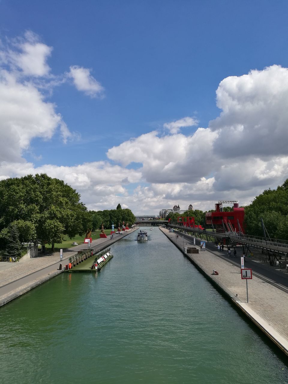 sky, tree, water, cloud - sky, river, bridge - man made structure, connection, diminishing perspective, tourism, waterfront, day, blue, travel destinations, cloud, canal, tourist, vanishing point, bridge, vacations, footbridge, long, city life, tranquil scene, the way forward