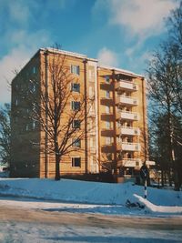 Built structure by frozen bare trees against sky