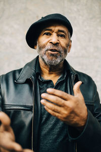 Portrait of senior man gesturing against wall