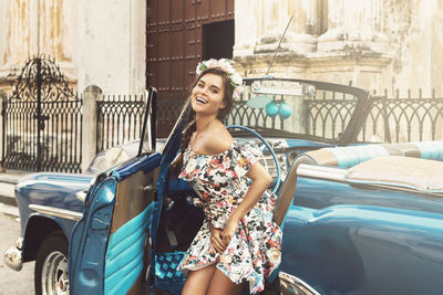 Portrait of young woman standing against car