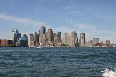 City skyline by sea against sky