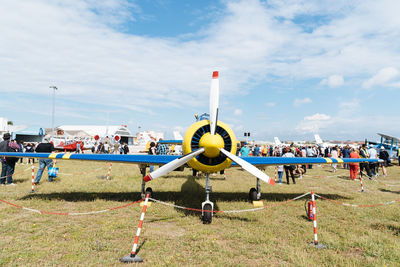 Group of people on airport runway against sky