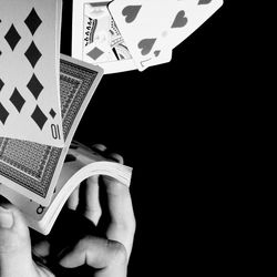 Close-up of hand holding book against black background