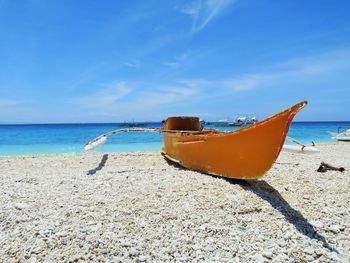 Boat moored on beach against sky