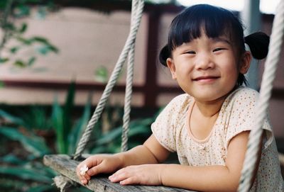 Portrait of cute girl on swing in yard