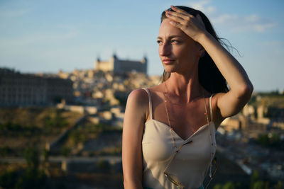 Young woman looking away against sky