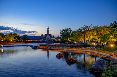 Scenic view of lake by building against sky at dusk