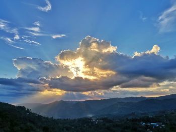 Low angle view of sunlight streaming through clouds