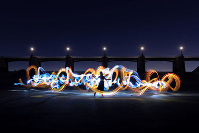 Illuminated light trails against blue sky at night