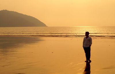 Full length of man standing at beach during sunset