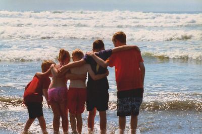 Rear view of friends standing on beach