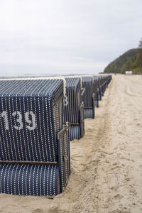 Deck chairs on beach against sky