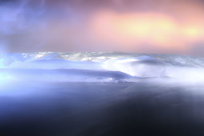 Close-up of snow on sea against sky during sunset