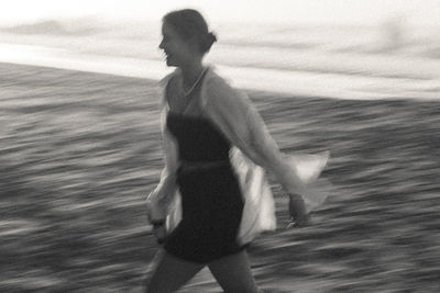 Full length of young woman running on the beach