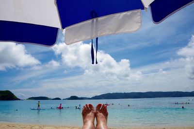 Low section of woman on beach against sky