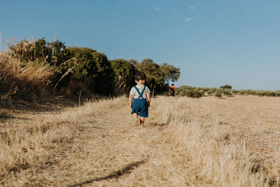 Rear view child walking on the fields