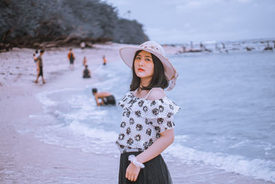 Portrait of young woman standing against sea